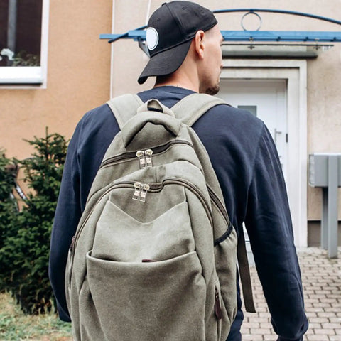 Person wearing a backpack with visible zipper pulls outside a building entrance
