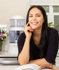 Smiling woman in kitchen with Replacement Filter For Gravity Water System That Reduces Fluoride And Chlorine in background next to flowers
