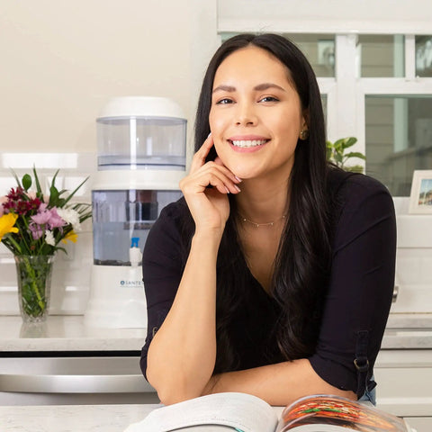 Smiling woman in kitchen with Replacement Filter For Gravity Water System That Reduces Fluoride And Chlorine in background next to flowers