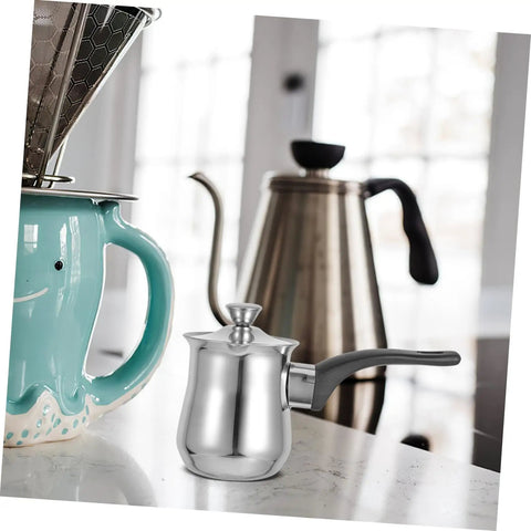 Stainless steel Turkish Teapot 180ml Milk Frothing Pot on kitchen counter, induction-ready, alongside other coffee brewing equipment.