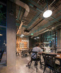 Modern industrial-style cafe interior with exposed pipes and varied seating.