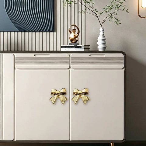 Six Piece Zinc Alloy Bow Drawer Knobs With Vintage Plating And Smooth Curved Handles For Dressers And Vanity Furniture Upgrades That Bring Main Character Energy To Your Space on a sideboard with a modern design.