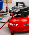 Six Gallon Pancake Air Compressor With 150 Psi Output And 2.6 Cfm Flow, Rock Hard Steel Tank, Padded Carry Strap, Non Slip Base, Hella Reliable Shop Beast For Weekend Grinds And Tailgate Tools In Vibrant Red with user working on wood.