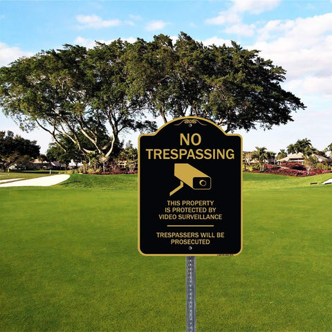 No trespassing sign in a park with tree background, text warns about video surveillance and prosecution.