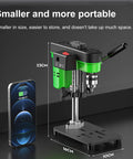 XVIIUIFOI Mini Drill Press With Dual Power Modes Adjustable Depth Control For Wood Metal Steel PVC Projects Ideal Benchtop Drilling Machine For Hobbyists And DIY Enthusiasts Compact Versatile Design next to smartphone for size comparison.