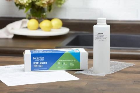 Convenient OMNIFilter Mail Home Water Test Kit with sample bottle and instructions on wooden table.