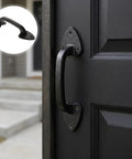 Heavy duty cast iron barn gate handle with aged iron finish and smooth curvature mounted on wooden door