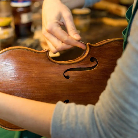 Person sanding a wooden violin using Top Notch Wet Dry Sandpaper Set 9 By 11 Inches With Grits 1500 2000 2500 3000 5000 7000.