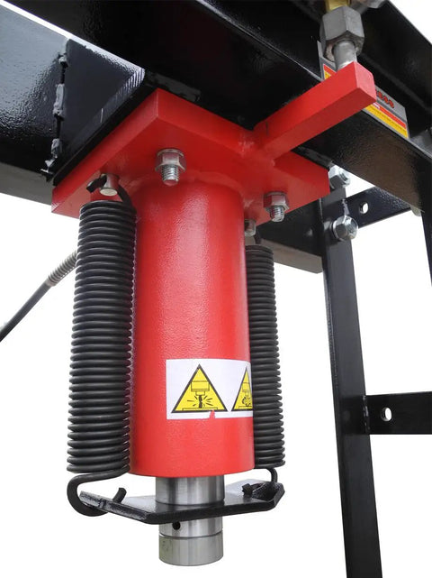 Close-up of the hydraulic cylinder of the Real Deal 40 Ton Air Hydraulic Shop Press with warning labels and metal components.