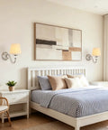 1-Light Brushed Nickel Vanity Light with Beige Fabric, Modern Wall Sconce above a white bed with striped bedding.