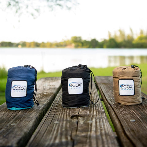 Three ecox outdoors parachute nylon hammock bags on a picnic table, including Parachute Nylon Hammock Single With 2 Tree Straps.