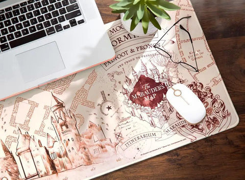 Harry Potter Marauder's Map Desk Mat XXL Gaming Desk Pad on wooden desk with laptop and plant; waterproof neoprene surface, non slip backing.