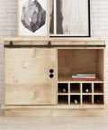 Light wood cabinet with sliding door and black handles, wine storage, and decorative art pieces on top against brick wall backdrop.
