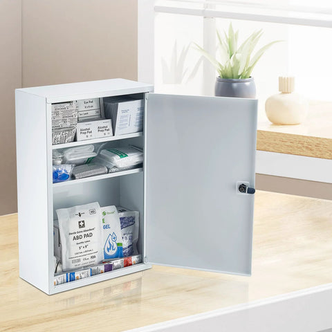 Front view of white metal three-shelf first aid cabinet with lockable door, opened to reveal bandages and supplies.