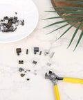 Ultimate Zipper Repair Kit With 61 Pieces including pins in sizes 3 5 8 10, latches, stops, and pliers on a marble surface