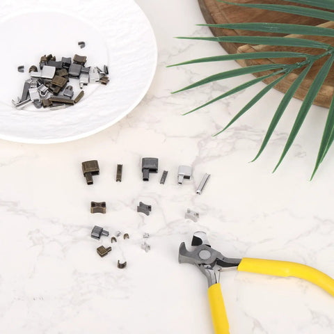 Ultimate Zipper Repair Kit With 61 Pieces including pins in sizes 3 5 8 10, latches, stops, and pliers on a marble surface