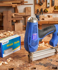 Premium 2 Inch 304 Stainless Steel Finish Nails 1000 Pack 16 Gauge Badass Brad Nails with a pneumatic nailer on a workbench.