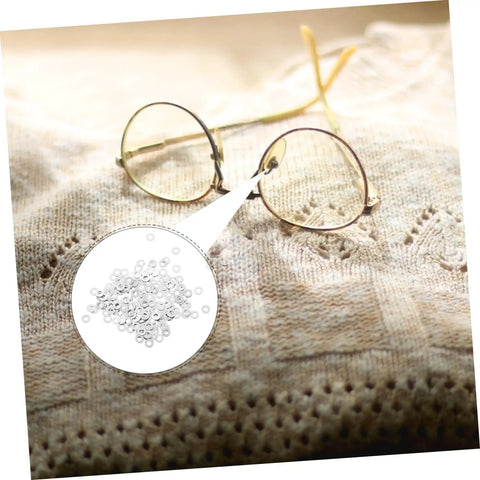 Close-up of gold rimless glasses on fabric with inset 200 Pcs Eyewear Rimless Glasses Washers Cushions Gaskets For Quick Repairs.