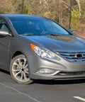 Front view of a gray Hyundai Sonata parked outside, showcasing the design of the 2011-2013 model in a sunny setting.