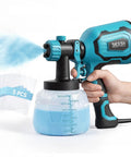 700W HVLP Paint Gun With Four Swappable Nozzles And Three Spray Patterns Featuring A Turbo Dust Blaster And One Push Clean System in use, spraying blue paint.