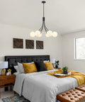 Modern bedroom with black and gold pendant light above bed, featuring Wagon Wheel Chandelier With Vintage Wood Grain Look, Dope 6 Light.