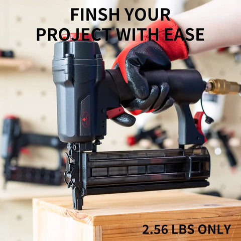Pro Grade 18 Gauge Pneumatic Brad Nailer And Air Powered 2 In 1 Staple Gun Kit held by gloved hand above wood.
