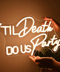 Til Death Do Us Party Neon Light Sign For Wedding Reception And Bridal Shower Backdrop Bedroom Wall Decor 17 Inch Warm White LED held by hands