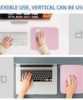 Person using a Pink Mouse Pad With Splash Proof Textured Surface And Stitched Edge For Desk, Non Slip Waterproof Rubber Base, 10.2 X 8.2 Inches, 3mm Thick, Rounded Corners, Cute And Durable Office Or Gaming Mat, placed beside a keyboard and laptop.