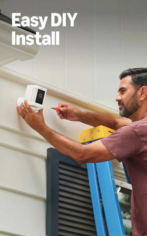 Ring Spotlight Cam Plus Battery outdoor security camera, white, being installed on exterior wall