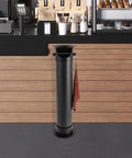 Floor standing espresso knock box, 34-inch tall, large capacity, in a cafe setting with anti splash deep bowl and towel hanging.