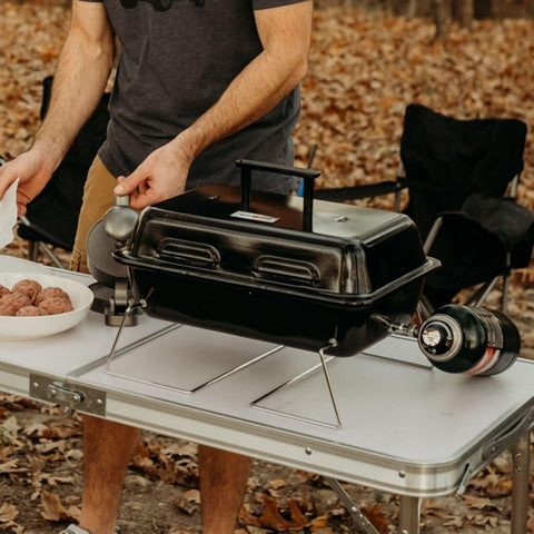 GPT 25 Propane Burner Grill With Foldable Legs For Camping And Tailgate Ready Portable BBQ Grill With Adjustable Regulator placed on a table outdoors