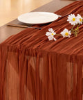 Rustic Terracotta Table Runner Hand Dyed From Breathable Cheesecloth bringing a warm vibe on a wooden table with flowers.