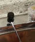 Front view of a chrome bathroom faucet with a crystal knob handle and a black knob on a granite countertop.