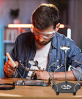 Man using Soldering Helping Hands With 3X Magnifying Glass 4 Rotatable Alligator Clips Magnetic Base Stand Gooseneck Arms for PCB repair