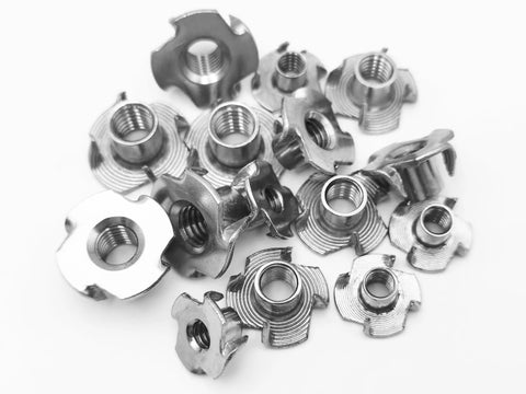 Premium Heavy Duty Stainless Steel Tee Nuts With Badass Four Prong Grip For Cabinetry Furniture And Rock Climbing Projects Featuring No Sweat Assembly In 1/4 5/16 And 3/8 Inch Sizes - assorted sizes in a pile.