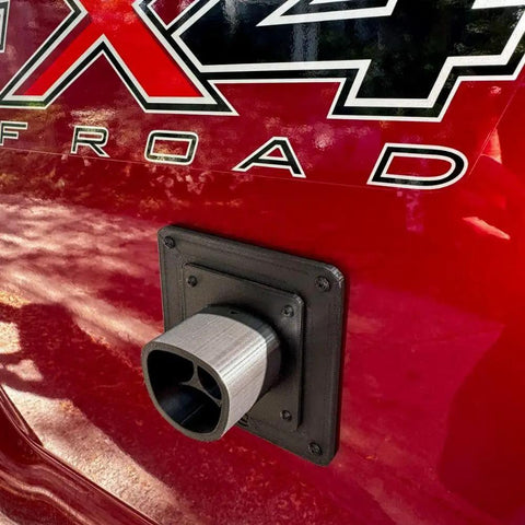 Fake EV Charging Port Magnet Snap On For Diesel Gas ICE Truck Gag Accessory mounted on a red truck near its logo.