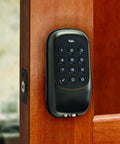 Black keypad deadbolt lock on wooden door, backlit keypad visible for Keypad Deadbolt Lock With Backlit Keypad, Auto Relock, And Custom Access Codes For Keyless Entry, Delete Codes Anytime, Keepin Your Home Safe In Satin Nickel Finish.