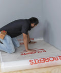 Installer laying Top Shelf 100 Square Foot Laminate And Engineered Wood Flooring Underlayment Roll on the subfloor.
