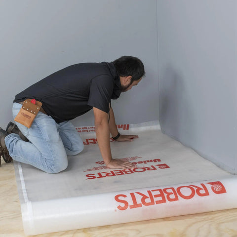 Installer laying Top Shelf 100 Square Foot Laminate And Engineered Wood Flooring Underlayment Roll on the subfloor.