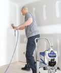 User operating Heavy Duty Cart Paint Sprayer With Full Control Flow And RAC IV Switchtip For Thick Coatings in a room.