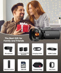Couple exchanging gift beside Ultra Dope 5K Video Camcorder, accessories shown: microphone, batteries, cables, SD card, bag, lens hood.