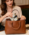 Woman placing Totally Clutch Vintage Rickshaw Bifold Wallet For Women Featuring Autumn Leaves Motif inside brown handbag.