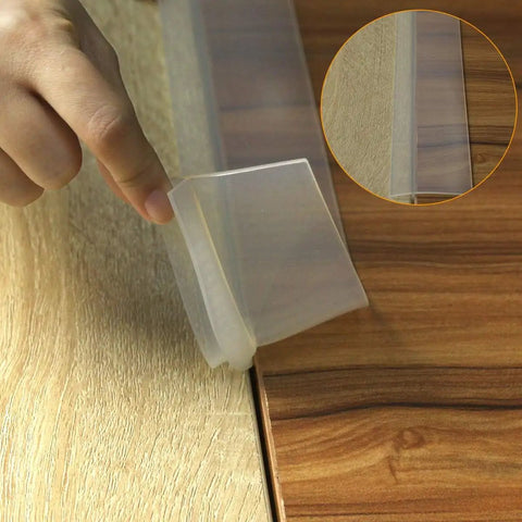 Two Pack 21 To 25 Inch Silicone Stove Gap Covers Flexible Food Grade Gap Filler For Kitchen Counter And Stovetop Semi Clear BPA Free Easy To Trim To Fit Keeps Crumbs And Spills From Falling Between Stove And Counter shown in use sealing gap between wooden countertop and stove top, hand shown adjusting position