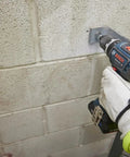One Half Inch Brushless Hammer Drill And Driver Kit With Core 18v 4ah Battery drilling into concrete block wall with LED lamp on.