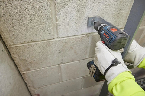 One Half Inch Brushless Hammer Drill And Driver Kit With Core 18v 4ah Battery drilling into concrete block wall with LED lamp on.
