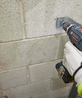 Rock Solid 1/2 Inch Hammer Drill Driver Kit Brushless Motor 565 In-Lbs Torque drilling into masonry wall with cordless tool.