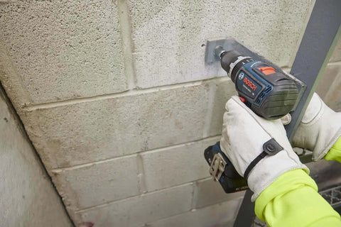Rock Solid 1/2 Inch Hammer Drill Driver Kit Brushless Motor 565 In-Lbs Torque drilling into masonry wall with cordless tool.