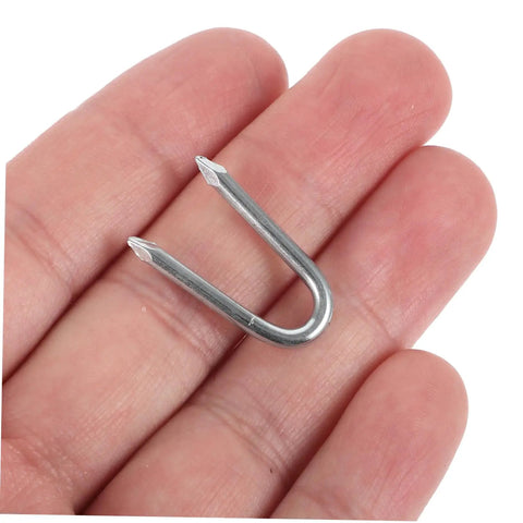 Close-up of a silver iron staple in hand, part of 50 Piece U Shaped Fencing Staples For Heavy Duty Iron Garden Nails Quick Install Sharp Tip