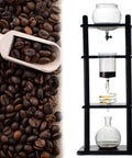 Premium Cold Brew Coffee Maker Featuring Slow Drip Glass Tower With Precision Valves For Ultra Smooth Low Acid Extraction Built Around A Slick Black Wood Base For Your Weekend Brew Crew with coffee beans and glass components.