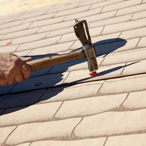 Hand using hammer to install One Inch Round Silver Plastic Cap Pack Of 2000 Count End Caps For DIY Projects on roofing sheet